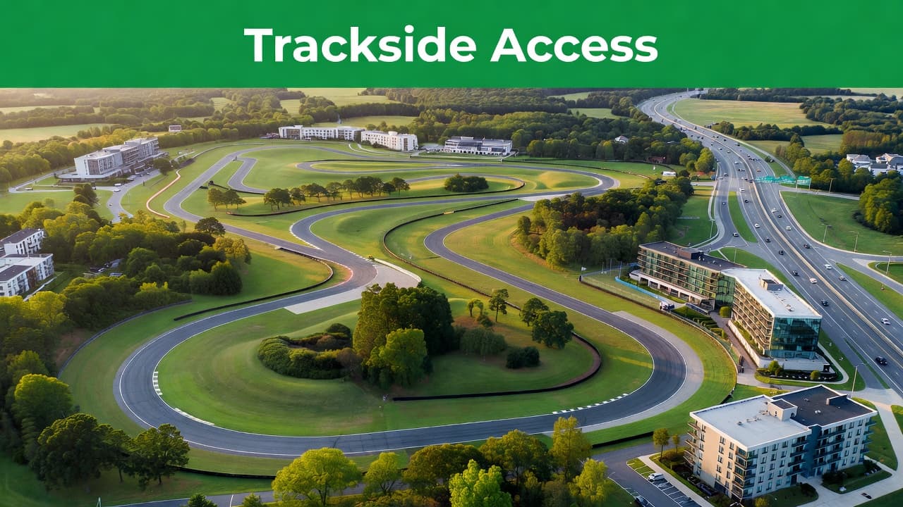 An aerial perspective captures the winding asphalt race track surrounded by rolling green hills and dense forest. A nearby highway provides clear access to the expansive sporting facility and surrounding grounds.