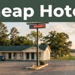 A budget roadside motel and glowing vacancy sign beside a quiet highway at sunset.