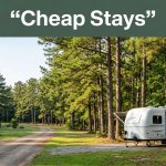 A travel trailer beside a tree-lined rural road under warm morning light.