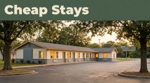 A clean roadside motel with warm lights glowing in the rooms at sunset.