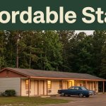 A modest motel with warm windows and a parked vintage car beside a quiet wooded road.