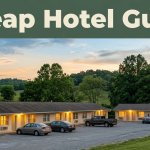 A modest roadside motel with warm window lights under rolling green hills at dusk.