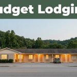 A modest roadside motel with glowing lights and a parked car against evening foothills.