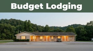 A modest roadside motel with glowing lights and a parked car against evening foothills.