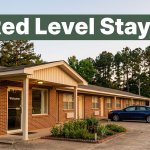 A modest brick roadside motel with warm evening lighting surrounded by rural pine trees.