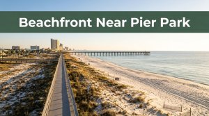 A beachfront hotel and walkway lead toward a pier and distant buildings.