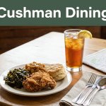 A Southern meal and iced tea sit on a rustic table beneath a Cushman Dining banner.