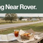 A takeaway meal and map rest on a picnic table beside a rural highway.