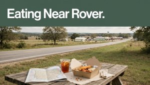 A takeaway meal and map rest on a picnic table beside a rural highway.