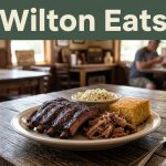 Barbecue ribs, pulled pork, cornbread, and coleslaw on a wooden table.