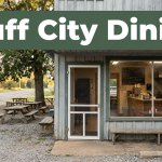 A rural barbecue storefront with picnic tables and a green Bluff City Dining banner.