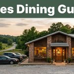 A brick roadside restaurant glowing beside parked cars and green countryside.