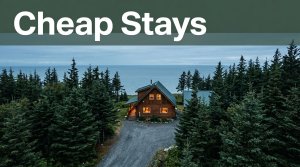 A warm cabin beside spruce trees and the Alaska coast under an overcast sky.