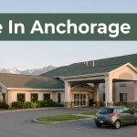 A hotel entrance with a rental car and Alaska mountains at sunset.
