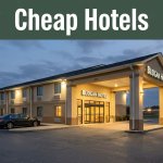 A warmly lit budget hotel entrance near I-85 in Lanett, Alabama, with a parked car outside.