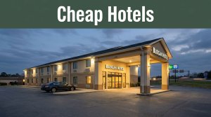 A warmly lit budget hotel entrance near I-85 in Lanett, Alabama, with a parked car outside.