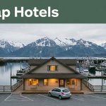 A small waterfront hotel and rental car sit beneath snowy mountains in Cordova, Alaska.