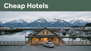 A small waterfront hotel and rental car sit beneath snowy mountains in Cordova, Alaska.