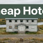A weathered lodging building near an Alaskan river with a suitcase in front.