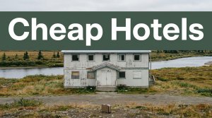 A weathered lodging building near an Alaskan river with a suitcase in front.