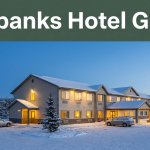 Warm hotel exterior beside snowy parking at winter dusk.