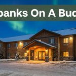 A budget hotel entrance beside snowy parking under a faint northern lights glow.