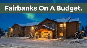A budget hotel entrance beside snowy parking under a faint northern lights glow.