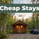 A cozy Fairbanks cabin hotel beside birch trees and a parked rental car at dusk.