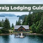 Rustic fishing lodge beside calm water with a dock, forest, and misty islands.