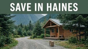 A small cabin and suitcase beside a gravel path in Haines, Alaska.