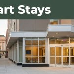 A budget hotel entrance at sunset with Union Station behind it and a green Smart Stays banner.