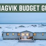A small lit hotel surrounded by snowy tundra near the Arctic sea.