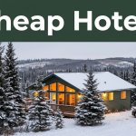 A warmly lit guesthouse among snowy spruce trees with a parked car in Fairbanks.