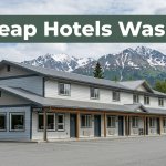 An affordable Wasilla motel with snowy mountains and greenery in the background.
