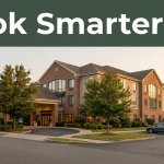 Hotel exterior beside a road with a parked car and a Book Smarter banner.