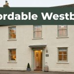 A welcoming Westbury B&B townhouse with warm windows and a suitcase by the entrance.