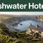 A coastal guesthouse overlooking Freshwater Bay with green cliffs, blue water, and a walking path.