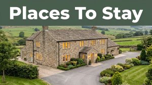 Stone inn with glowing windows beside green countryside and a neat driveway.
