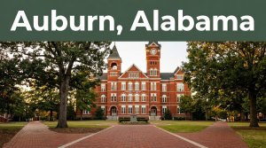 Samford Hall framed by oak trees and brick paths beneath an Auburn, Alabama banner.