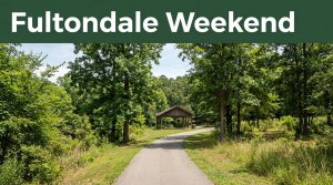 A green park trail leads to a wooden pavilion beneath trees, with a dark-green Fultondale Weekend banner above.