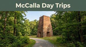 Historic red-brick furnace surrounded by forest and a winding trail.