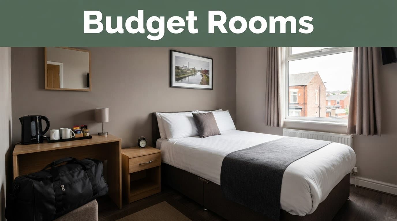 A modest hotel room with a made bed, desk, kettle, and travel bag.