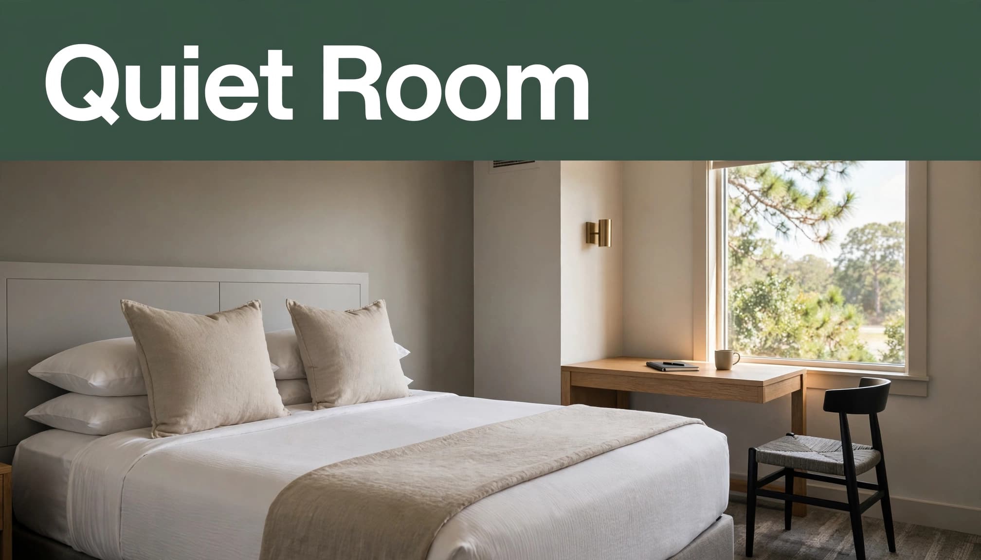 A tidy hotel room with a king bed, desk, neutral decor, and sunny window.