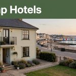 A modest guesthouse near Hastings pier with luggage by the entrance at sunset.