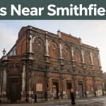 Historic red-brick Smithfield Market buildings beneath a green banner in morning light.