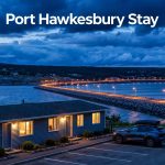 A roadside motel and car overlook the Canso Causeway at blue hour.