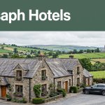A countryside hotel near St Asaph with a car, green hills, and the cathedral in the distance.