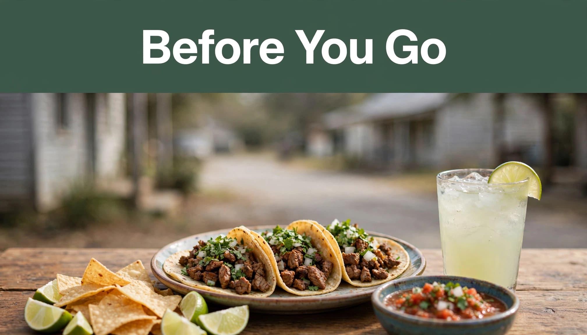 Street tacos, chips, salsa, lime, and a cold drink on a wooden table.