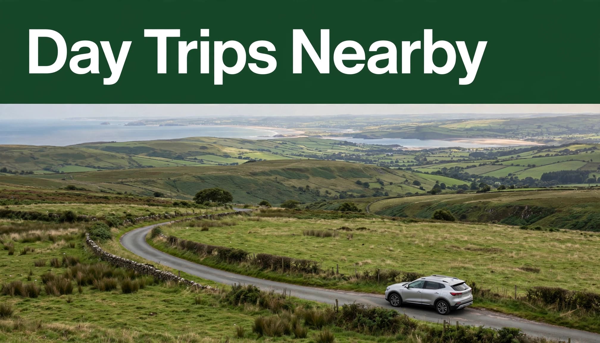 An empty rental car beside a winding road with green hills and a distant coast.
